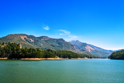 白天蓝天下碧海旁青山褐岭